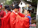 50个民族70对情侣“单身节”在广东东莞凤岗镇举行多民族特色集体婚礼。图为身穿民族特色服装的新人们在台下互相帮忙整理服装。　安致标 摄 - 新浪广东