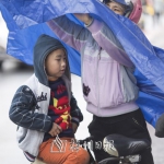 家长给孩子披上雨衣。（林翔　摄） - Meizhou.Cn