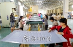 富胜公司工人在65寸曲面电视机后盖板生产线上作业。 - Meizhou.Cn