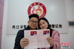 资料图：2016年2月14日，在四川省内江市东兴区婚姻登记处，一对新人在展示刚领取的结婚证书。兰自涛 摄 - 广东电视网