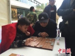 图为国际象棋大师吕钦在惠州市举办的“名人象棋对抗赛”上，观看并指导来自北京棋手操向农在与棋手刘青峰的对袂。　宋秀杰 摄 - 新浪广东