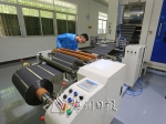 金华达公司技术人员在检查经涂布后制成的锂电池正极极片卷。（高讯　摄） - Meizhou.Cn