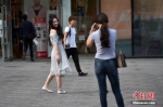 图为北京三里屯街头的姑娘小伙们换上夏装出行。 中新网记者 金硕 摄 - News.21cn.Com