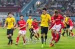 双方球员在比赛中争抢头球（红衣为梅县队球员）。（连志城　摄） - Meizhou.Cn
