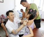 古展枫为小女孩患者敷定喘药膏。（张炳锋　摄） - Meizhou.Cn
