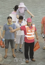 尽管天气炎热，文明交通志愿者始终在街头引导交通。（林翔 摄） - Meizhou.Cn