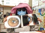 女子展示其受伤眼睛的照片。图片来源：香港《明报》 许芳文/摄 - 新浪广东