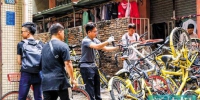 ■工作人员清理城中村内乱停放的共享单车。 - 新浪广东
