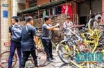 ■工作人员清理城中村内乱停放的共享单车。 - 新浪广东